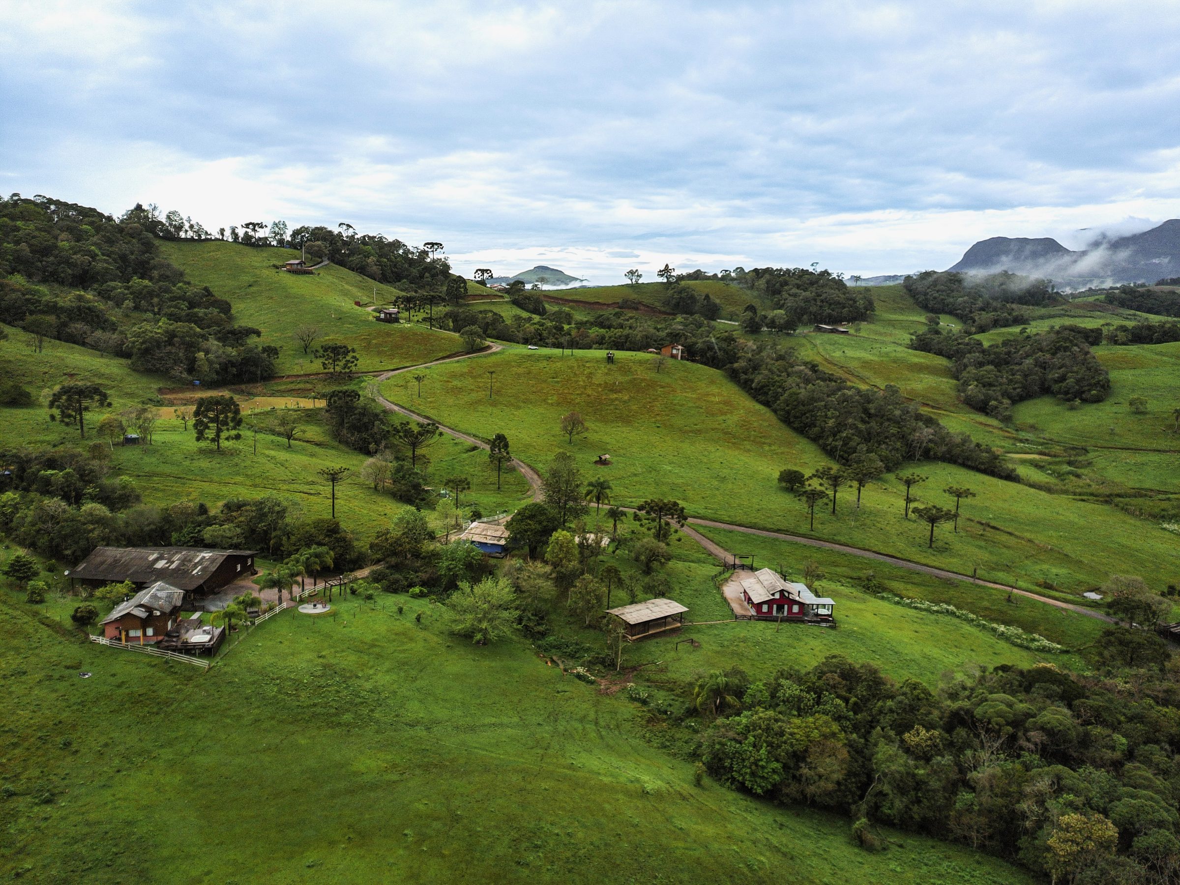 Vista aérea do Sítio Recanto Azul, com os chalés entre os campos e as montanhas